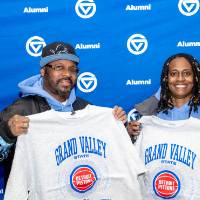 Two people holding up their crewnecks as they pose for photo
